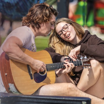 Two students play guitar and sing on campus. 