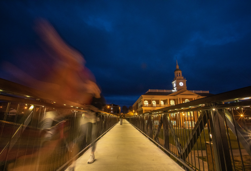 A student walks across the viaduct at night. 