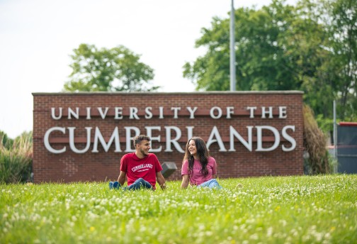 Two students relax in front of Cumberlands welcome sign 