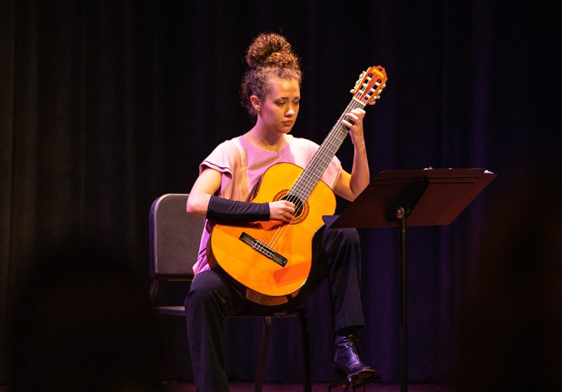 A student performs with her guitar during a music event